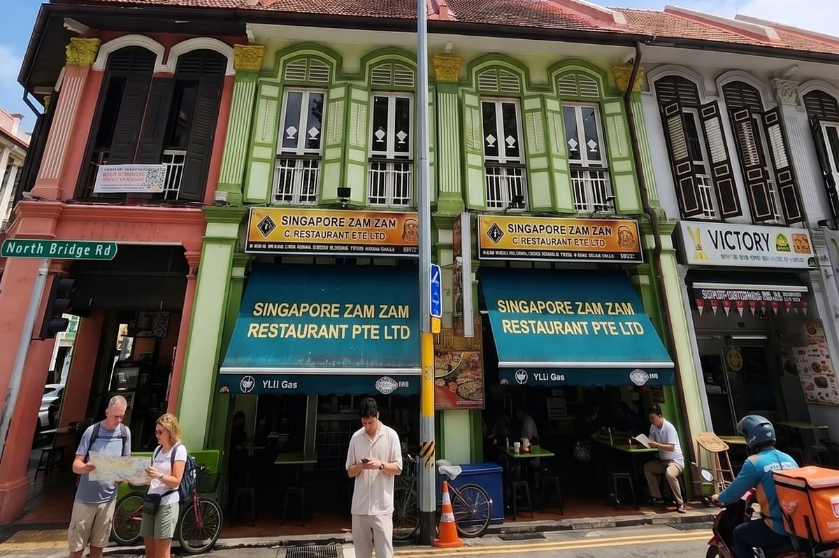 The exterior of the historic Singapore Zam Zam Restaurant on North Bridge Road, featuring its iconic green facade and teal awnings.