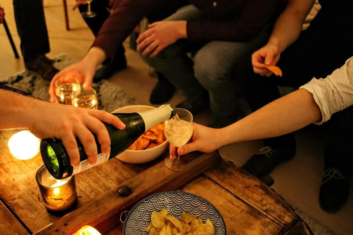 Friends seated at a table filled with wine and food, illustrating the theme of community building through shared meals.