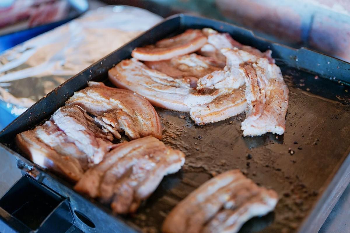 Grilled pork meat on a greasy pan