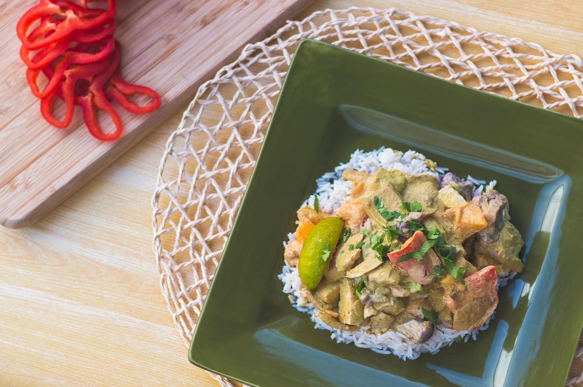 A warm plate of rice and curry with a lime wedge on a table.