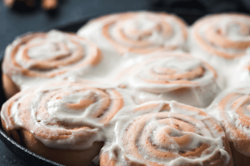 Close-up of a fluted flan mold showing a rich, dark caramel glaze dripping down the textured sides of the golden custard.
