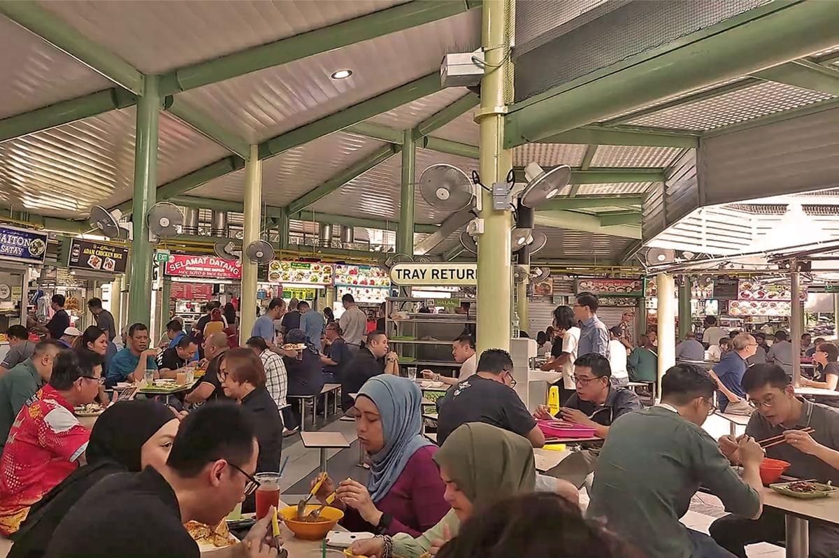 people eating and lining up inside a food court with green and white details