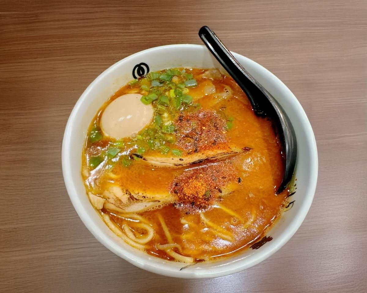 A bowl of Menya Musashi’s soup curry with rich broth, tender vegetables, and perfectly cooked meat, served in a Japanese-style ceramic bowl.