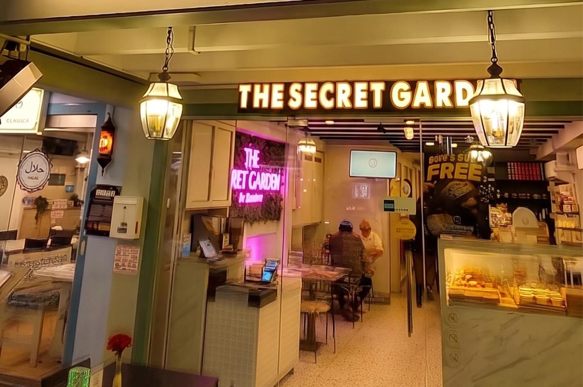 Entrance to The Secret Garden restaurant, featuring warm hanging lamps and a neon interior sign.