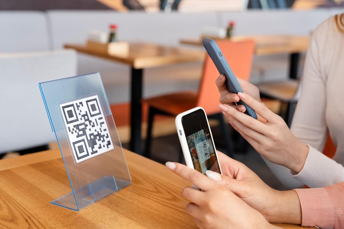 Two people scanning a QR code, may it be to order or to pay.