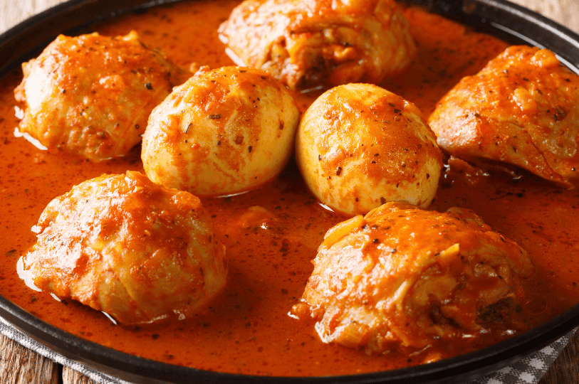 A macro shot of Doro Wat highlighting the texture of the chicken skin and the bold, spicy red sauce typical of this classic Ethiopian stew.