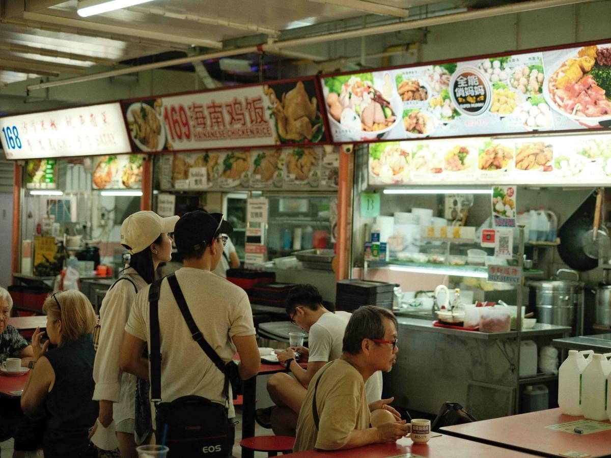 Busy hawker stalls laid out side by side as people dine in.