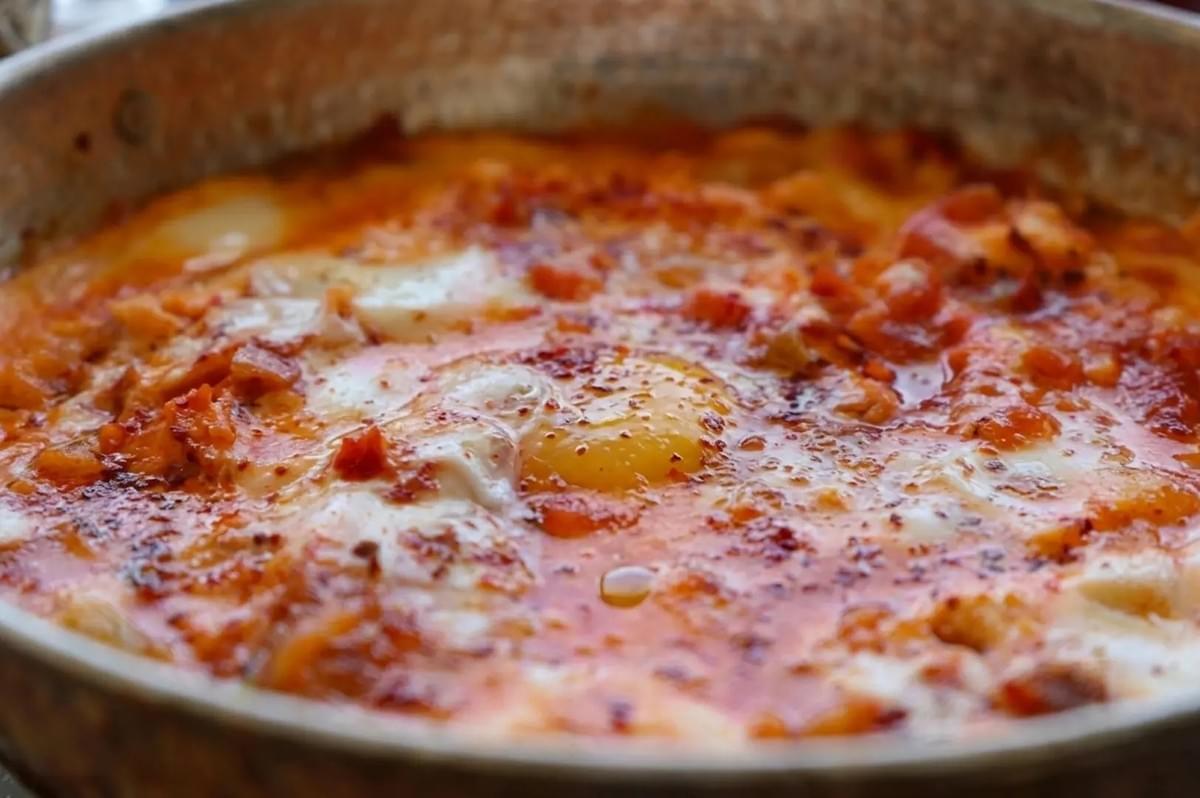 Close-up of Menemen, a spicy Turkish scrambled egg dish with tomatoes and peppers simmering in a traditional copper pan