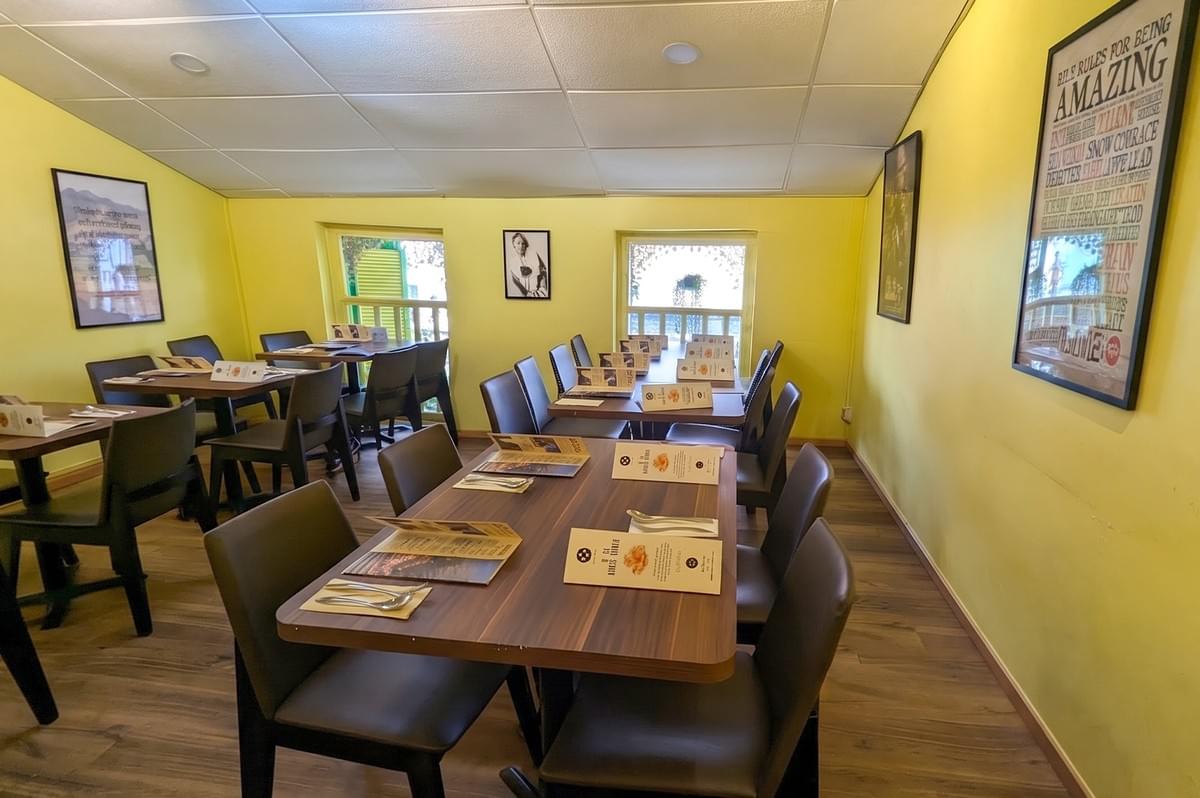 Cozy indoor dining area at Positano Risto featuring wooden tables, dark leather chairs, and warm yellow walls.