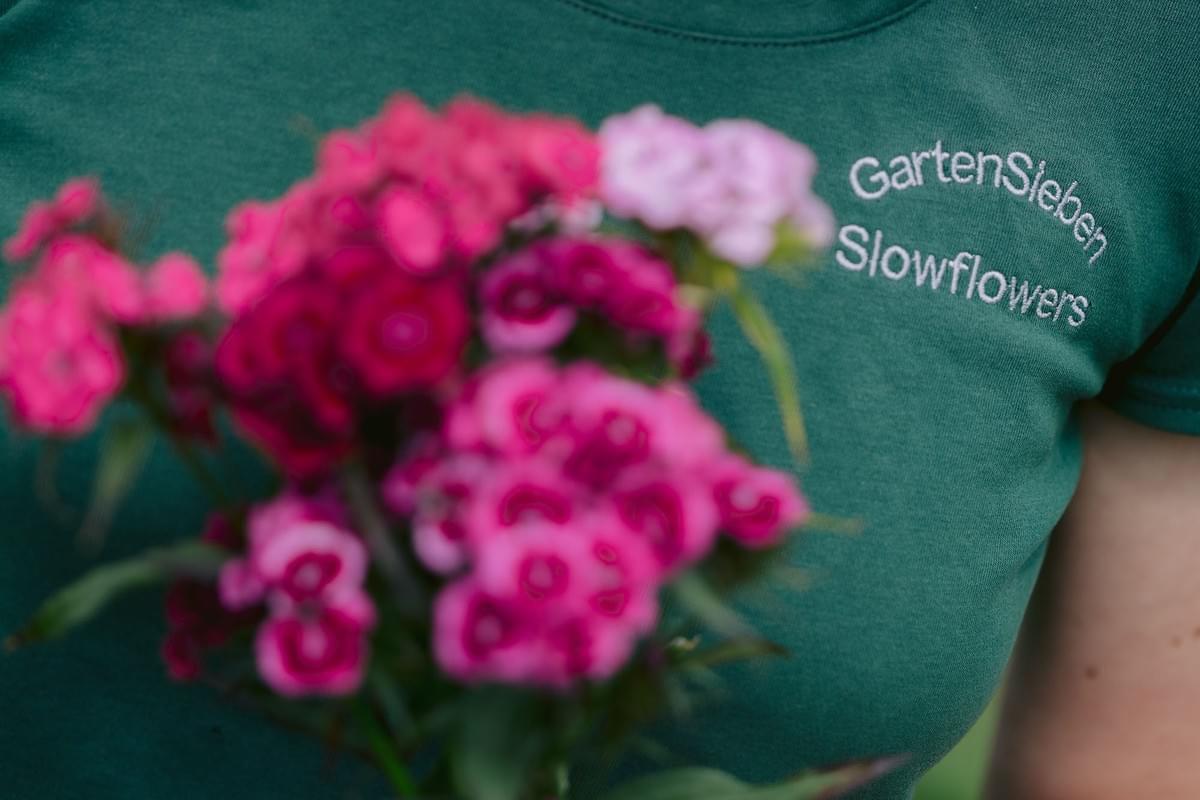 Ein Firmenlogo auf einem T-Shirt und davor Blumen