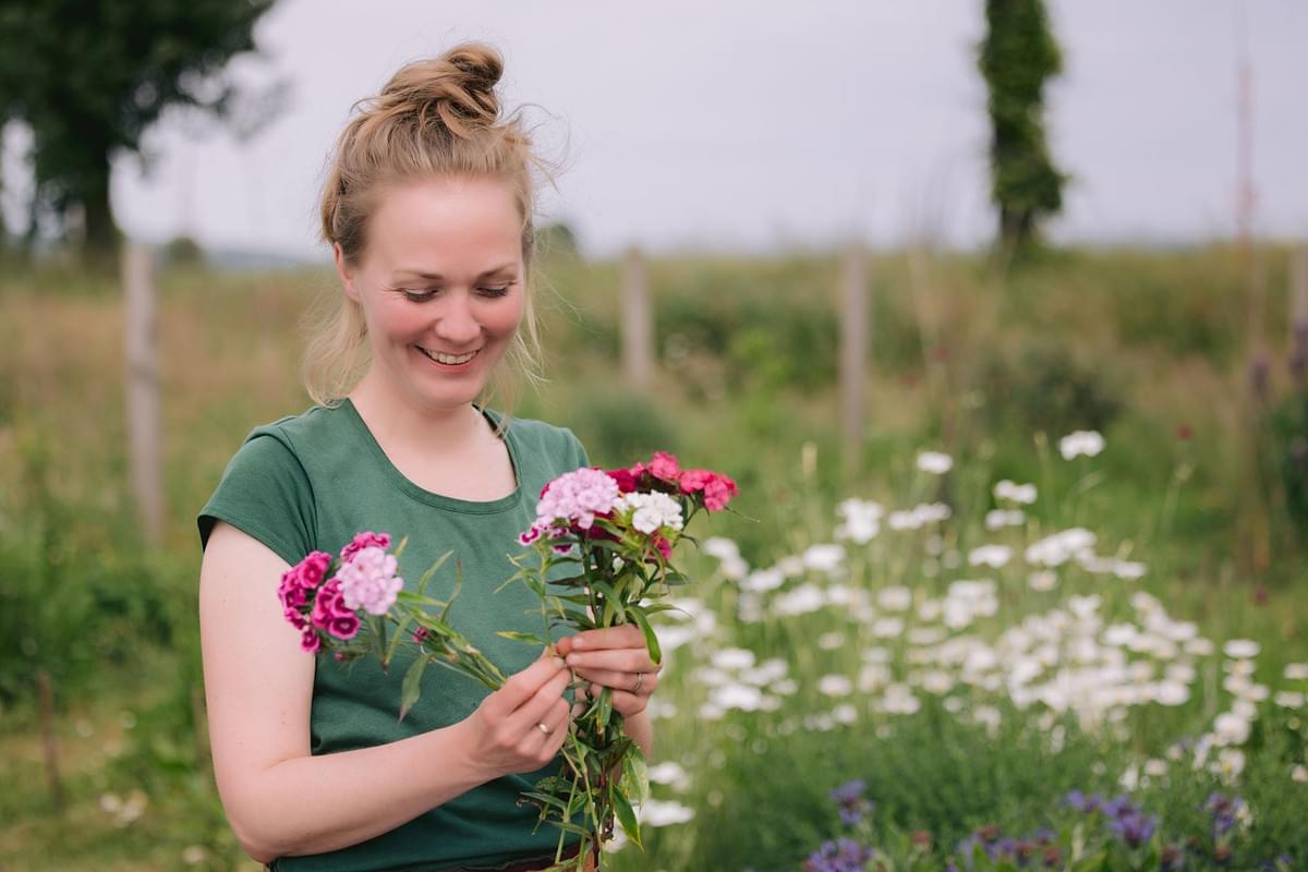 Portrait einer jungen Frau mit Blumen in der Hand im Garten