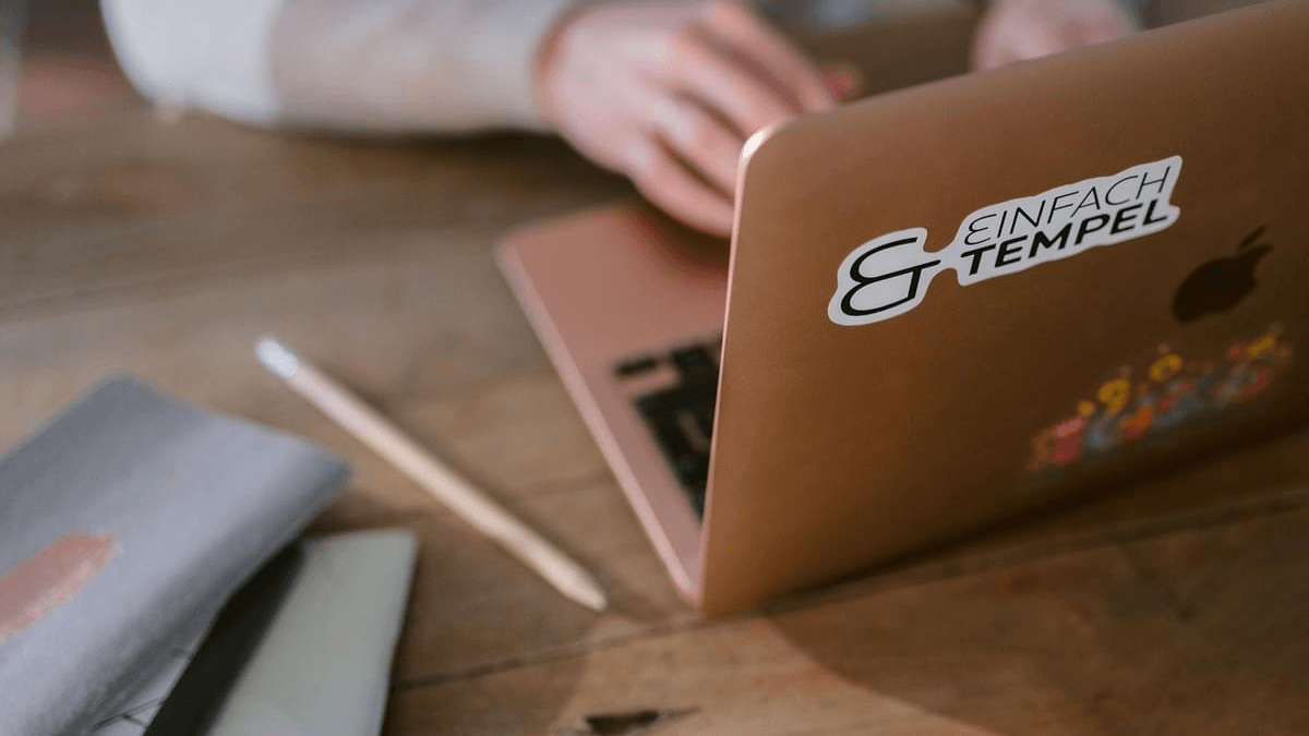 Notizbuch, Bleistift und Laptop auf einem Schreibtisch