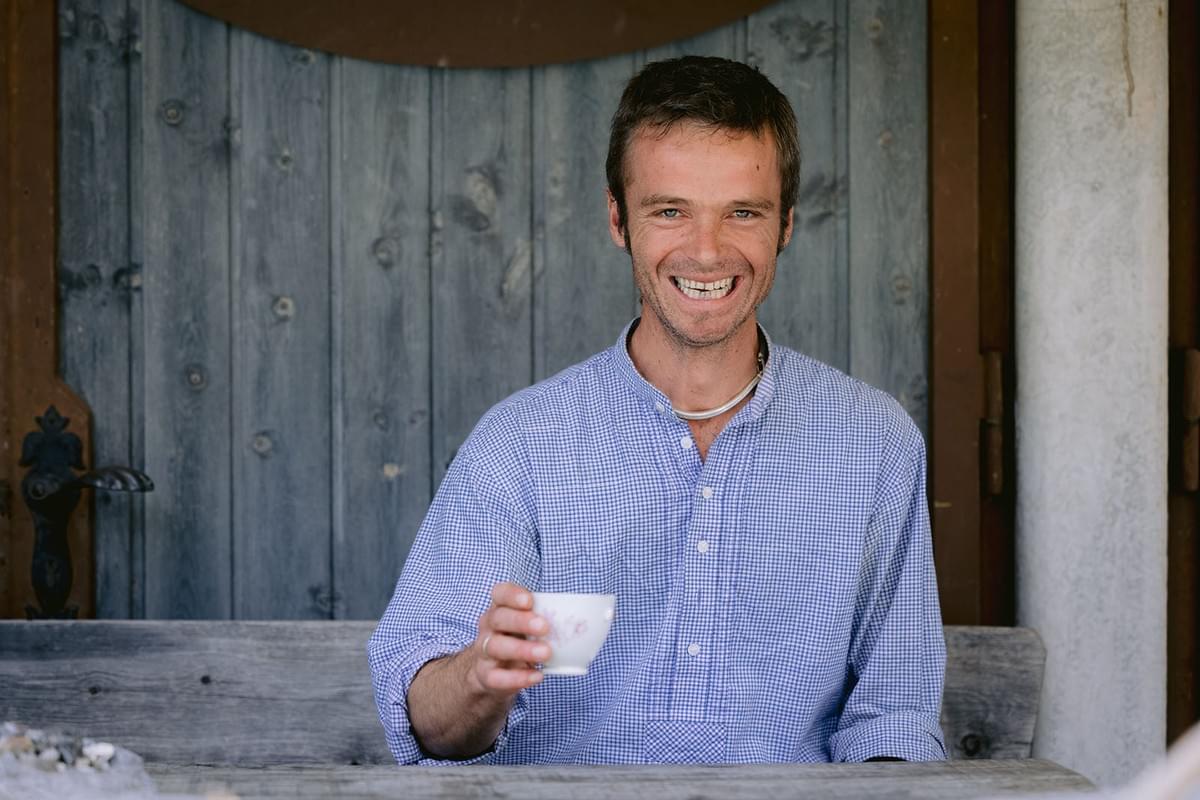 Portrait von einem Mann vor einer Holzwand mit Kaffeetasse in der Hand