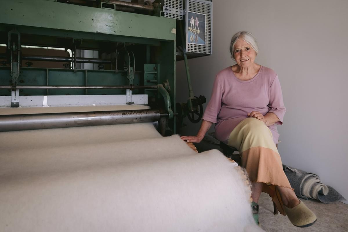 Portrait alte Frau an Wollverarbeitungsmaschine