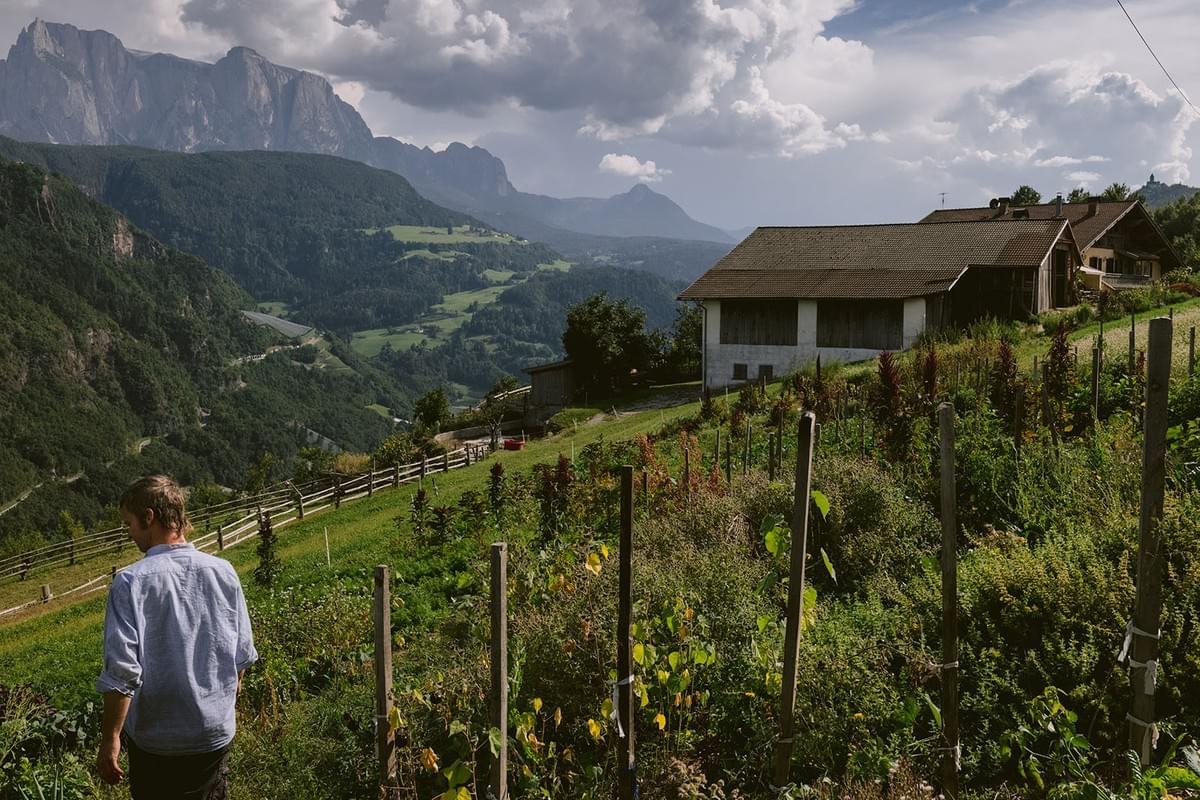 Ein Bauer geht durch seinen Garten mit Blick auf Berge