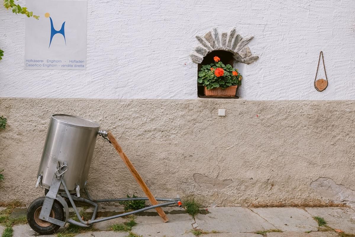 Milchkanne vor Hauswand