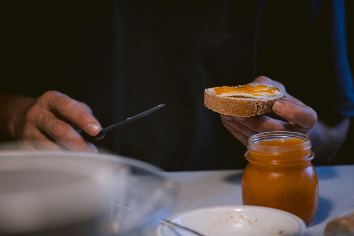 Mann am Frühstückstisch mit Brot in der Hand