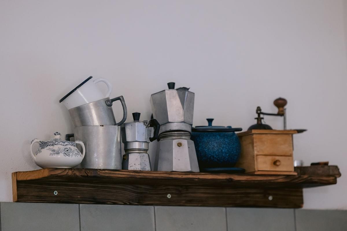 Verschiedene Kaffeemühlen und Kocher auf einem Küchenregal