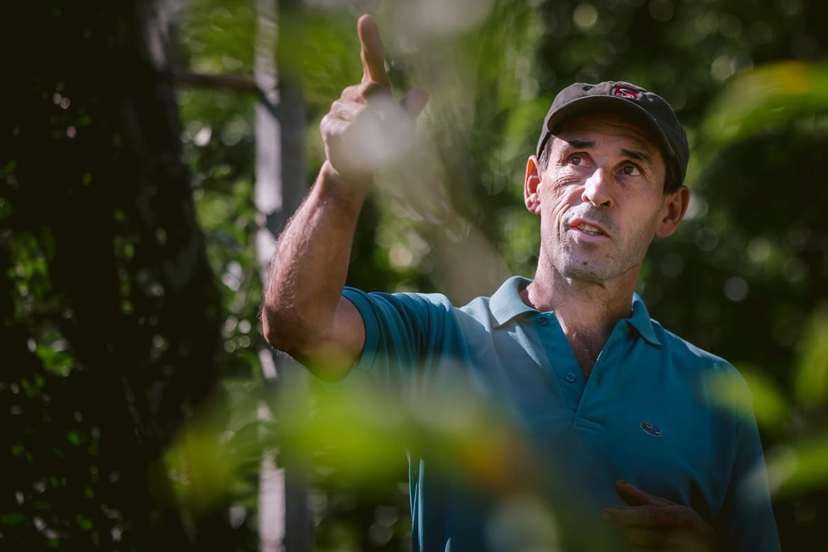 Ein Bauer zeigt mit dem Finger auf die Früchte in seinen Obstbäumen
