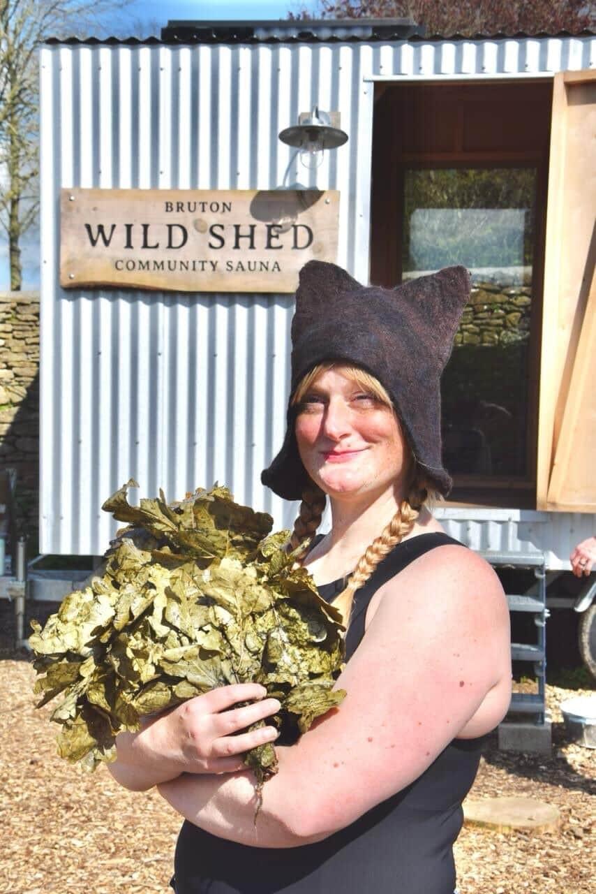 Sauna svend Emilie Joy Rowell outside a sauna wearing her handmade woolen sauna hat.