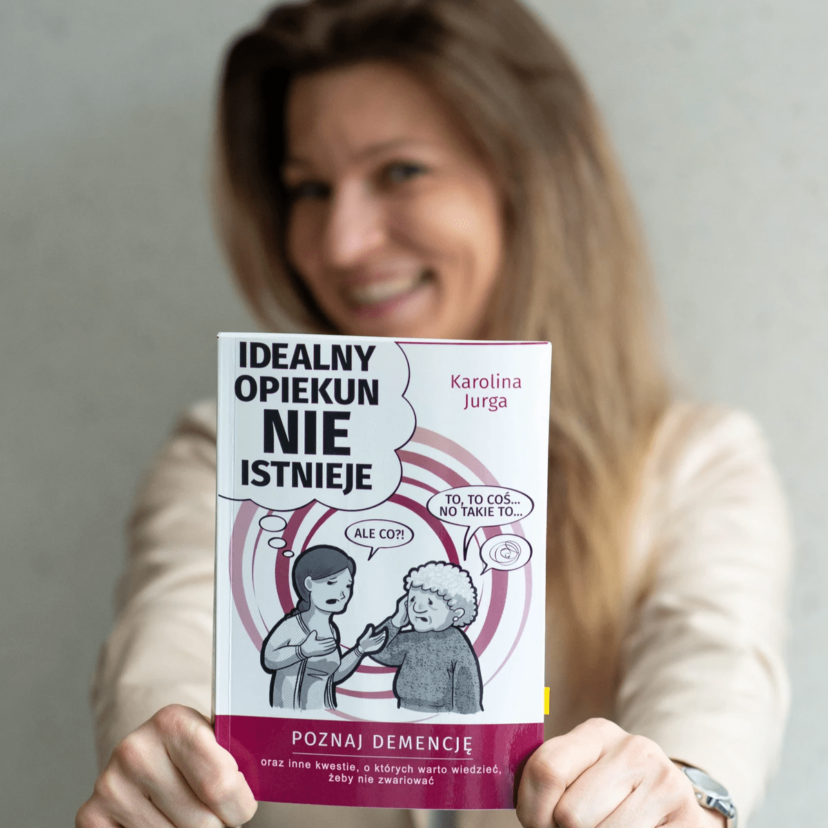 Uśmiechnięta kobieta trzymająca w rękach książkę "Idealny opiekun nie istnieje"