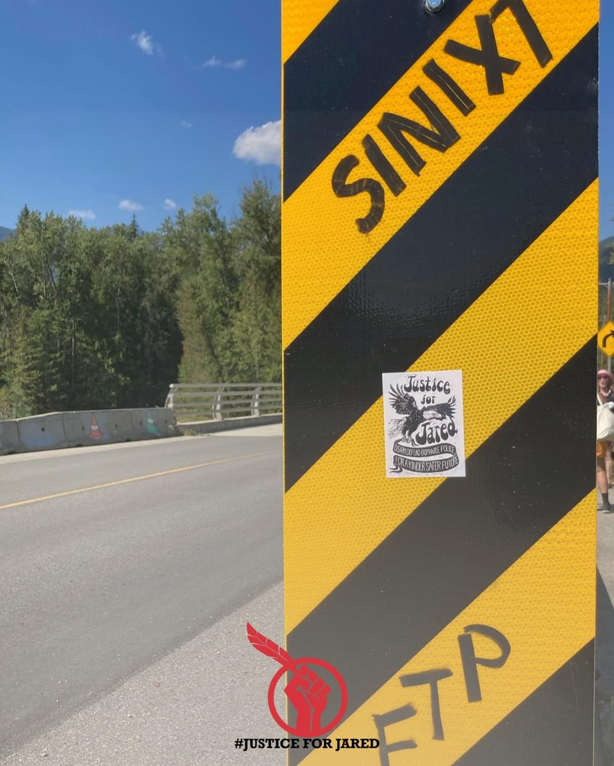 A graffitied roadside sign (black and yellow diagonal stripes) with the text “SINIXT” and “FTP.” A black and white Justice For Jared sticker is stuck in the centre. At the bottom of the graphic is the Justice For Jared logo, a red fist holding up an eagle feather.