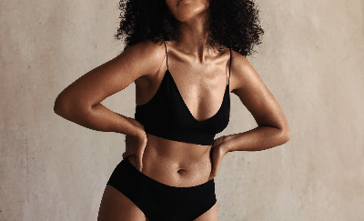 Woman in sports bra measuring waist, representing weight loss journey and body confidence Woman in sports bra measuring waist, representing weight loss journey and body confidence
