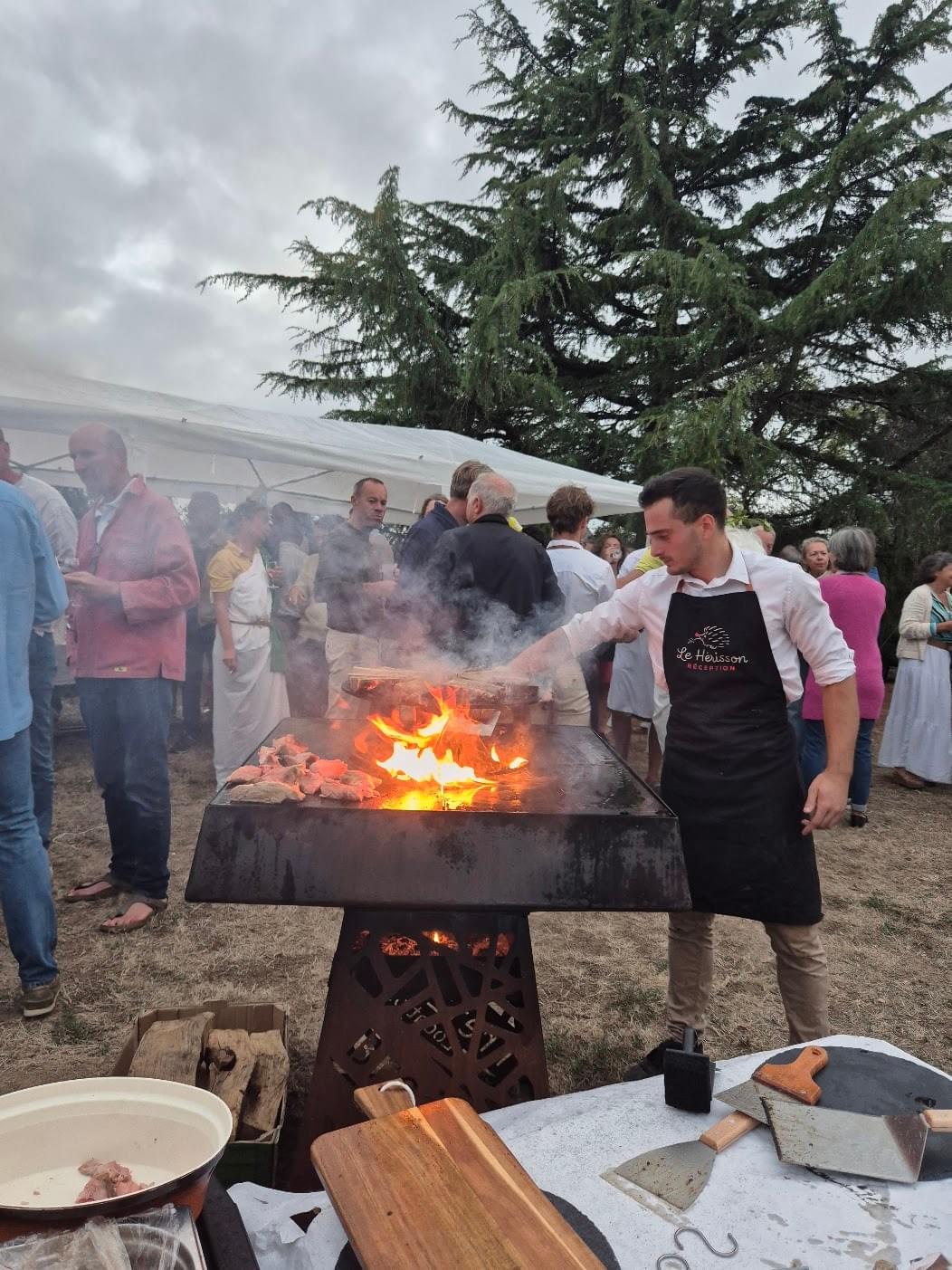 Le chef saisit des pièces au brasero devant les invités d'un cocktail