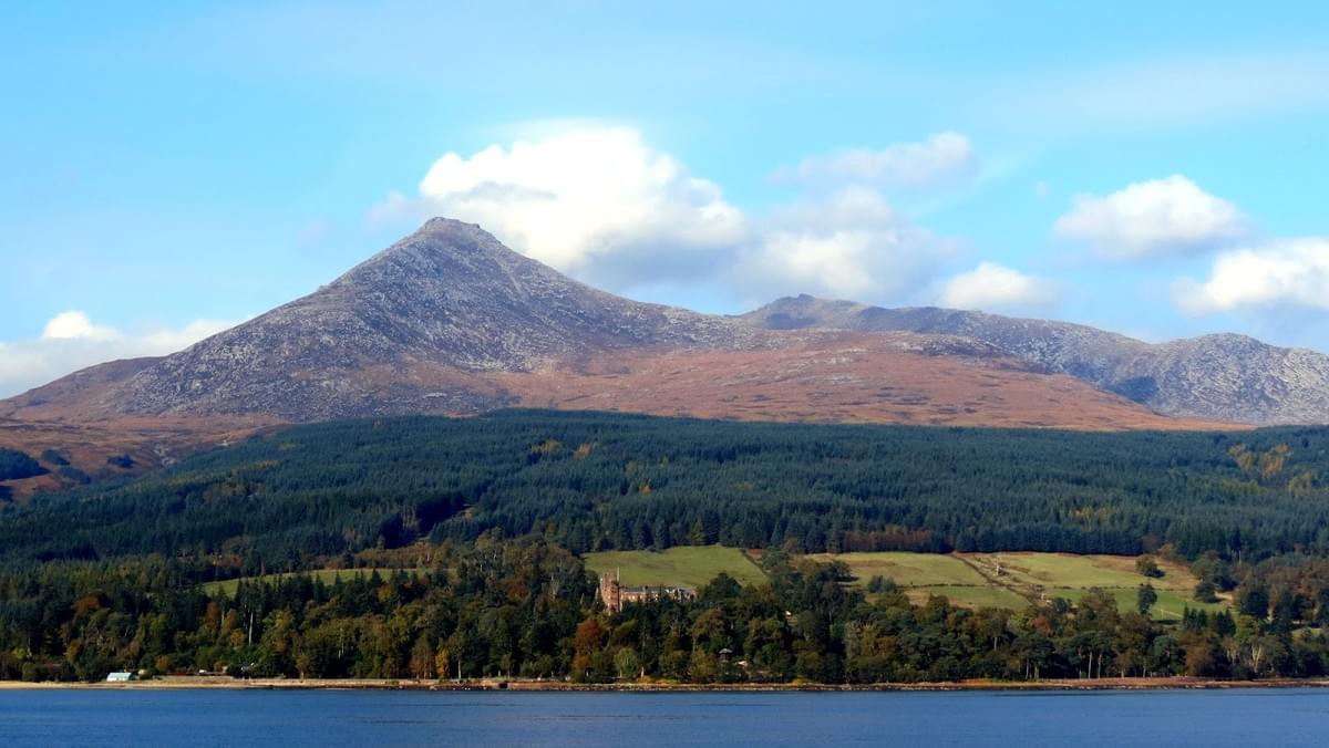 Étendue d'eau au premier plan avec paysage semi montagneux et boisé derrière. Un vieux château écossais au bord de l'eau derrière un petit bois et aux pieds des montagnes. Étendue d'eau au premier plan avec paysage semi montagneux et boisé derrière. Un vieux château écossais au bord de l'eau derrière un petit bois et aux pieds des montagnes.