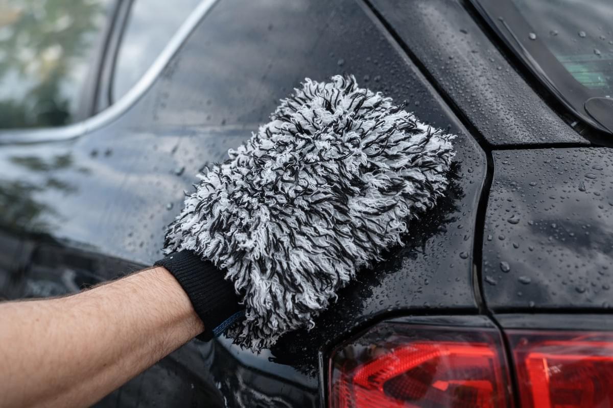 Nettoyage d'une carrosserie automobile avec le gant carbonfaser éliminant les traces