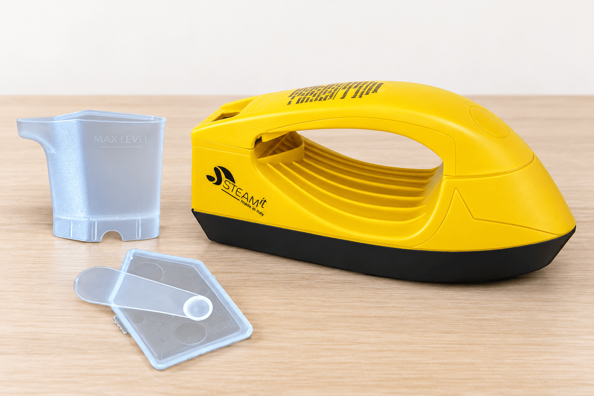 Steam-it jaune avec son gobelet doseur d’eau et sa dosette transparente posée sur le couvercle du compartiment
