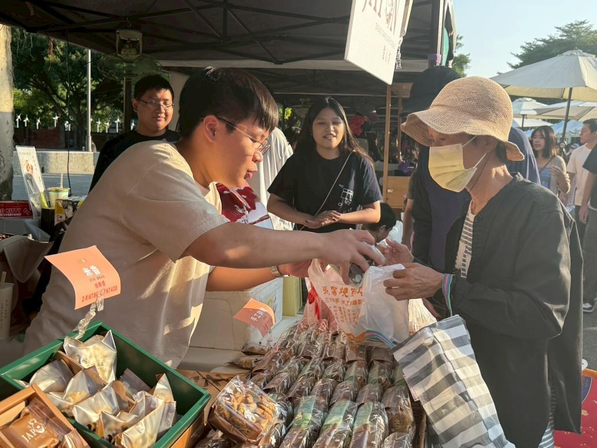 「暖暖堡」成員陳柏翰（左）協助顧客將手工餅乾裝袋。