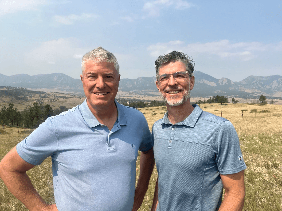 Jeff Caliguire and Jason Malec standing outside with mountains in the background