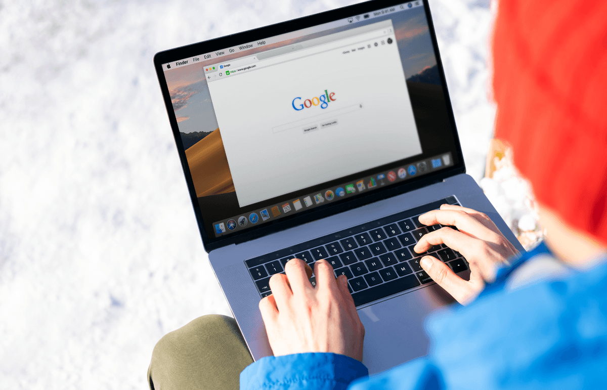 A person with a laptop resting on their knee types on the keyboard to perform a Google search.