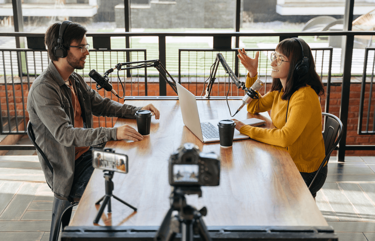 Alt text	Un homme et une femme assis face à face à une table en train d’enregistrer un balado et filmés par un téléphone et une caméra vidéo.	A man and a woman sit face to face at a table recording a podcast, being filmed by a phone and a video camera.