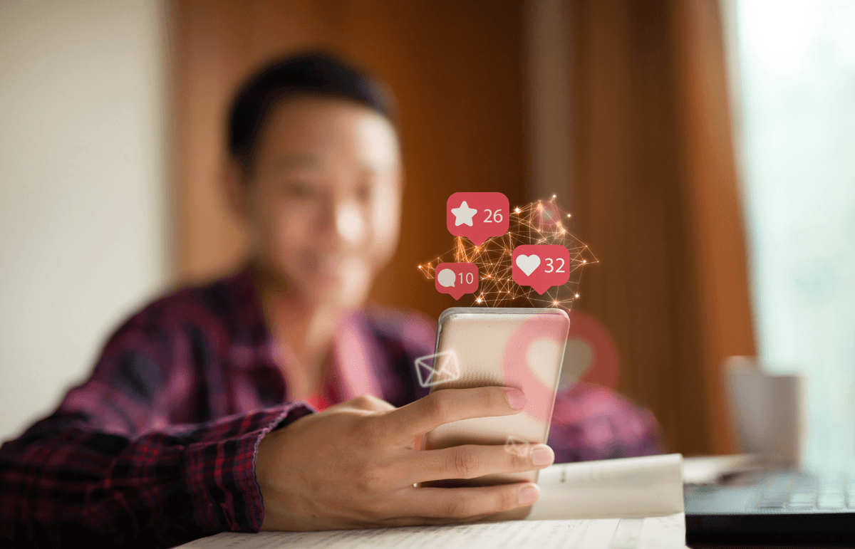 A man in a blurred background, viewing social content on the smartphone in his hand.