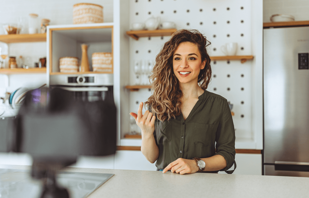 A content creator standing in a kitchen filming niche content for her followers.