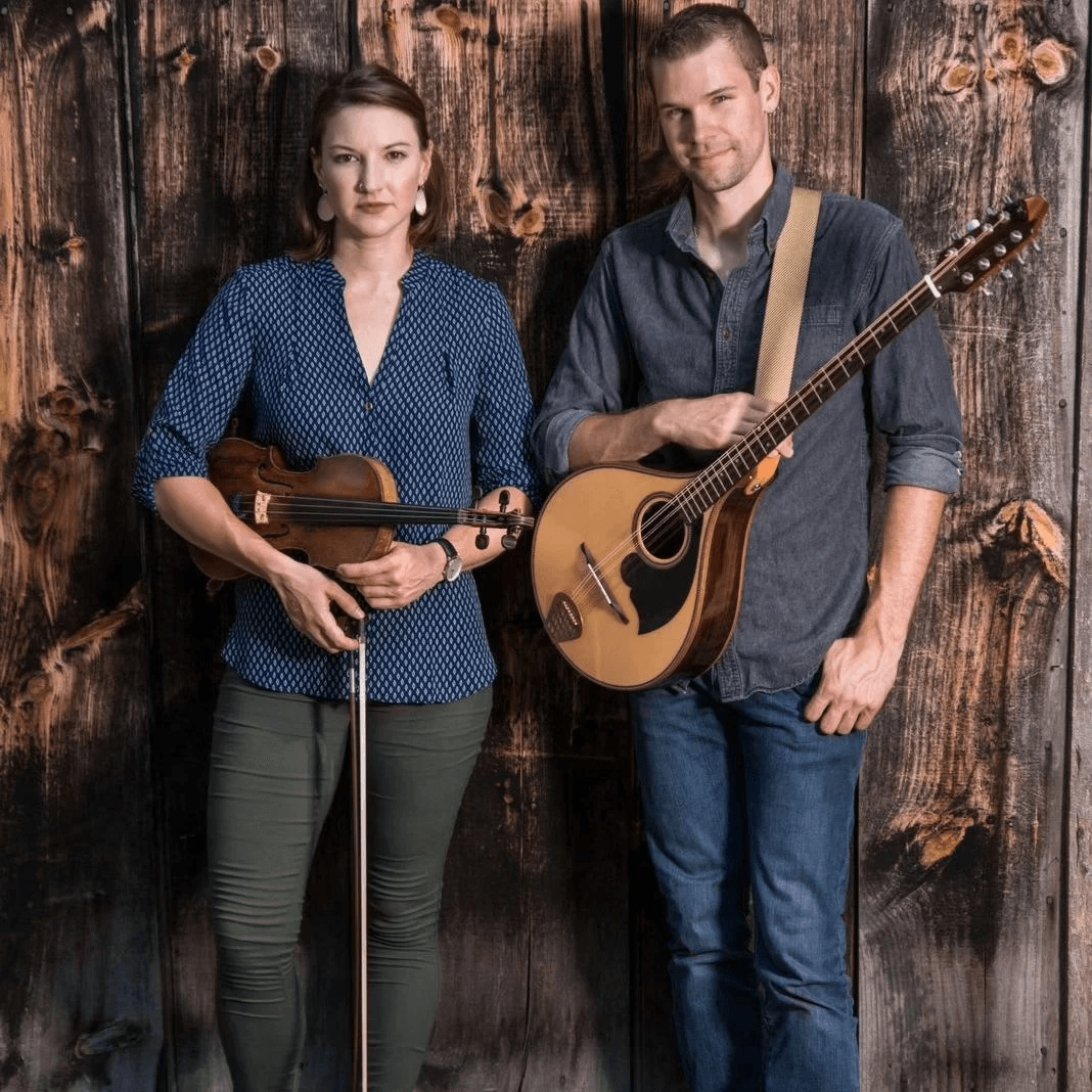 Deirdre Lockman standing with fiddle next to Corey Purcell standing with instrument.
