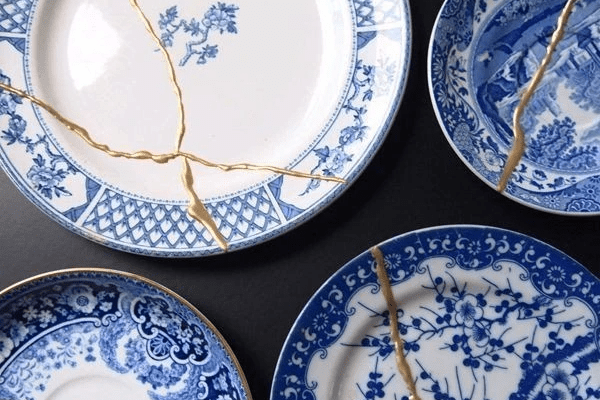 A photo of blue and white China plates with golden cracks on some.