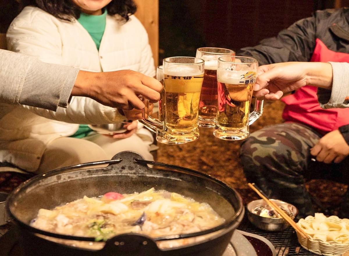 和心村の冬の夕食で、鍋を囲んで乾杯する人たち