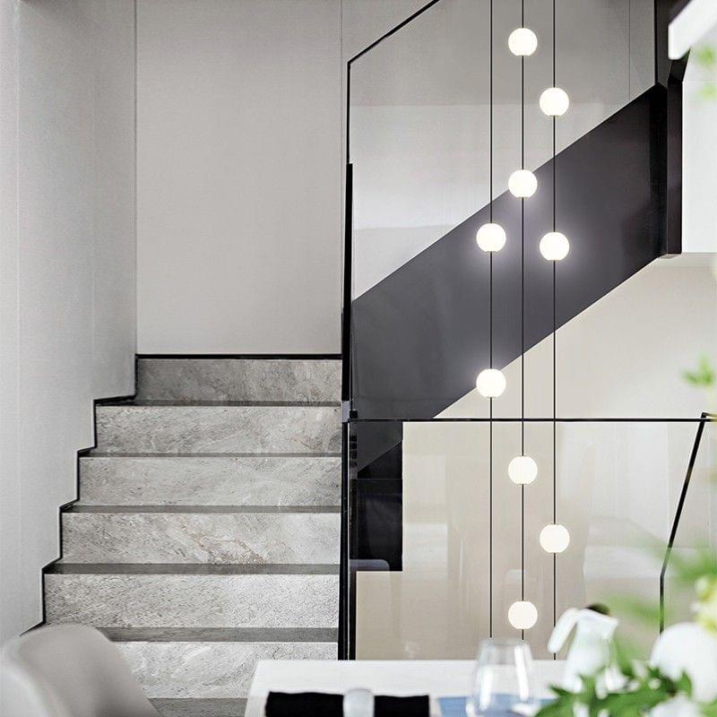 Minimalist long metal tube pendant light for narrow stairwell, ideal for modern vertical spaces and high ceilings.