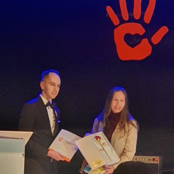 Zdjęcie przedstawiające Iwonę Janicką (po prawej) i Jarosława Gębalę (po lewej) trzymają w rękach dyplom, symbol róży