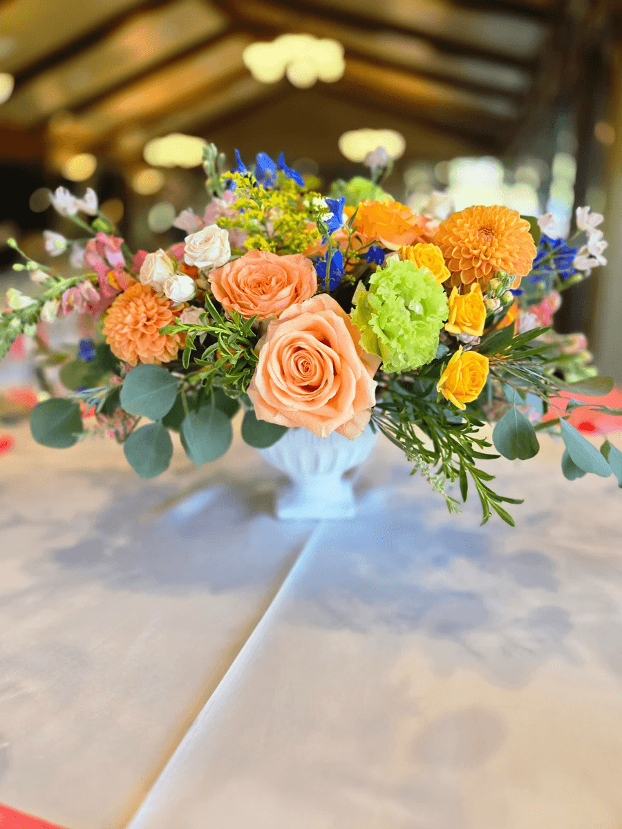 Colorful low floral centerpiece with bright orange and green