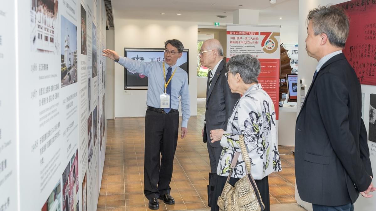 圖書館校史組館員何政興（左一）為野依良治教授伉儷介紹本校發展大事紀。（攝影／秘書處揭維恆）