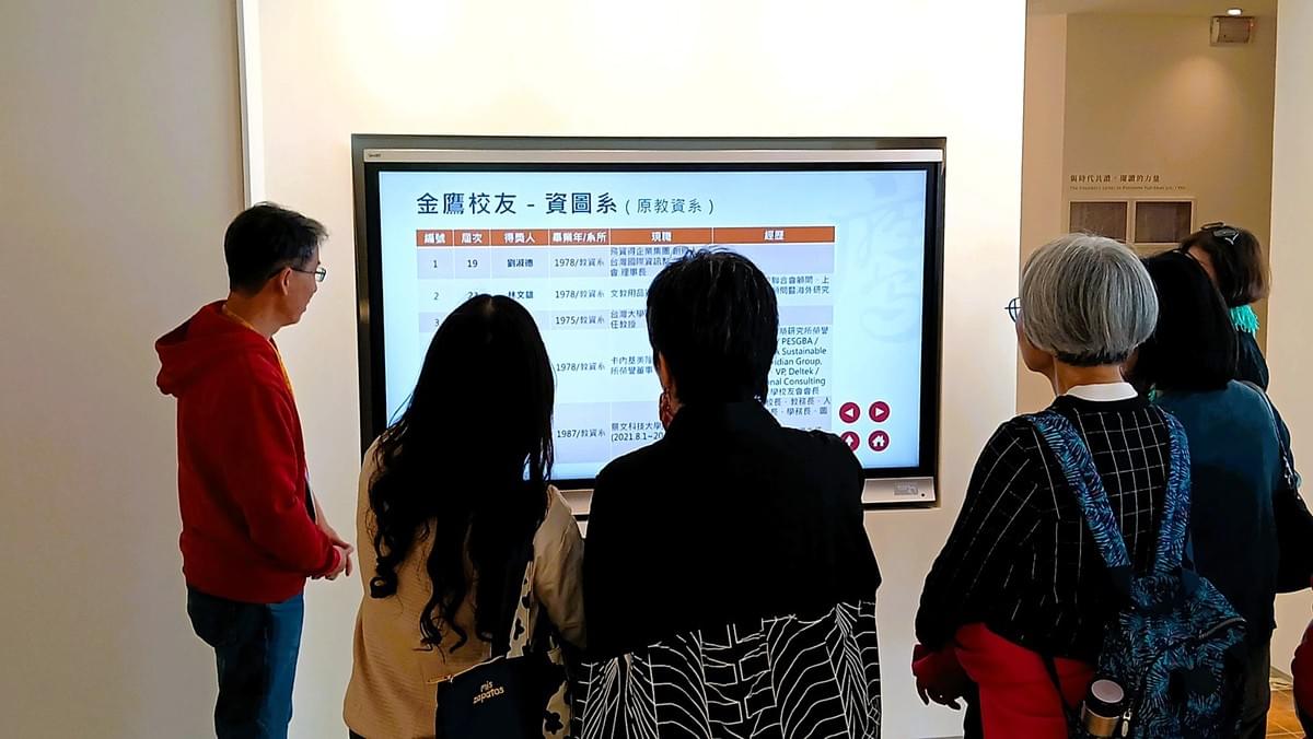 教資／資圖系第20屆系友返校參加「教資傳情．圖憶永恆—教資／資圖55回娘家」活動，並特別蒞臨校史館參觀。由同班同學、現任校史組館員何政興（左一）親自導覽，於「大事紀ing」展區中介紹最新完成、依系所分類整理之金鷹校友資料，呈現各系所校友於不同領域的卓越表現。（攝影／圖書館鄒姍熹）