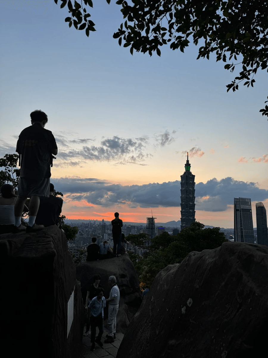 The sunset view of the Taipei 101 with a crowd at the top of the Elephant Mountain