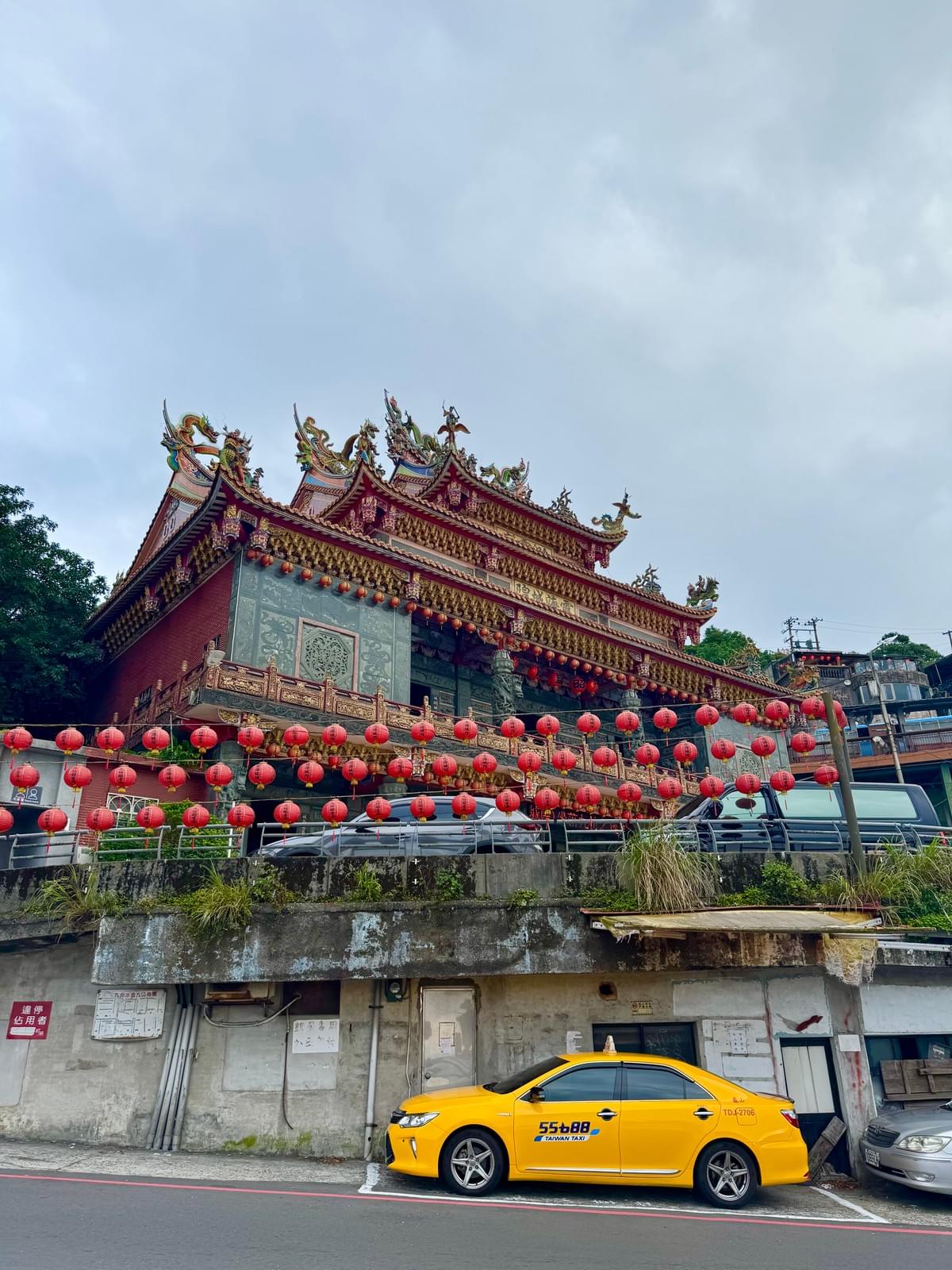 The temple at the top of the Jiufen Old Street mountain with red lanterns and yellow cab