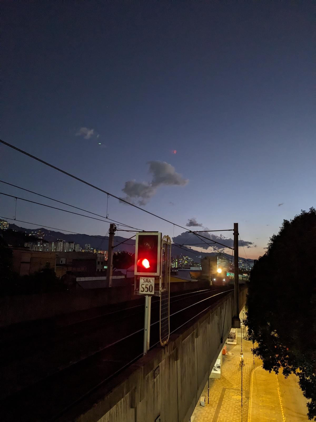 Medellín Metro train arriving at a station with the sun setting in the background