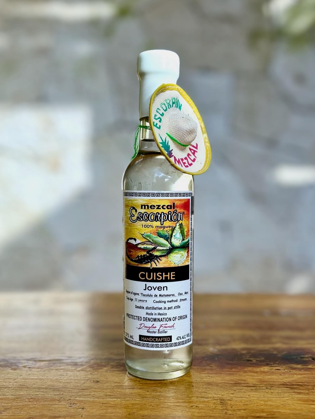Bottle of Escorpion Cuishe mezcal on a rustic wooden table. 