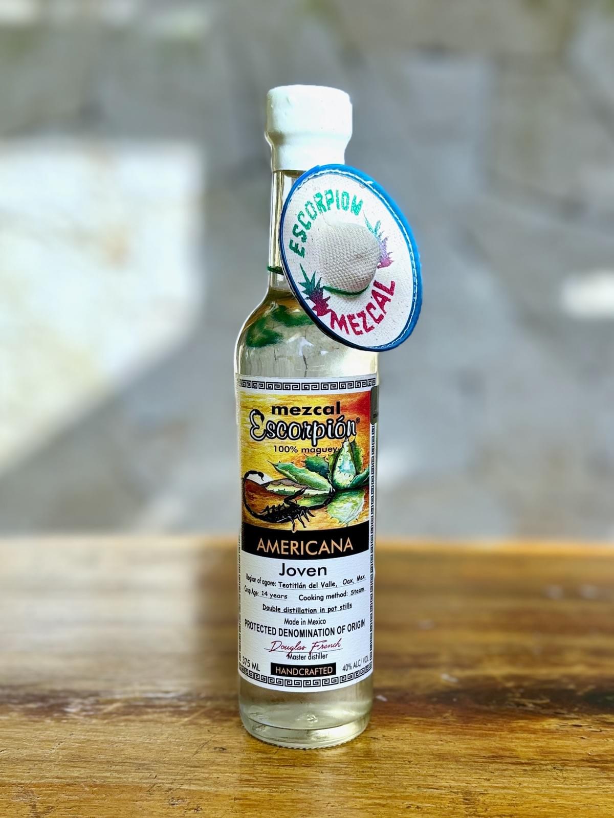 Bottle of Escorpion Americana mezcal on a rustic wooden table. 